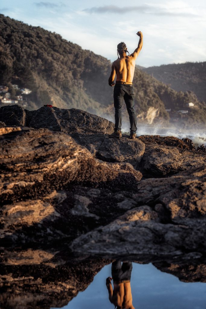 Persona levantando el brazo con energía sobre las rocas en Maicolpue sur de Chile
